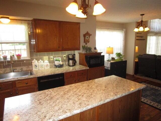 5669 Maplewood Ct, Lewis Center, OH 43035 - kitchen featuring a chandelier, black dishwasher, brown cabinetry, tasteful backsplash, and dark wood finished floors