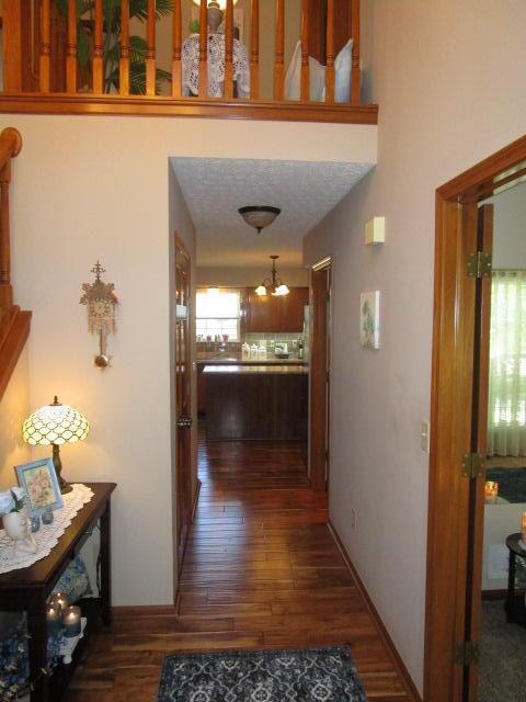 5669 Maplewood Ct, Lewis Center, OH 43035 - hallway featuring dark wood-style flooring and a chandelier