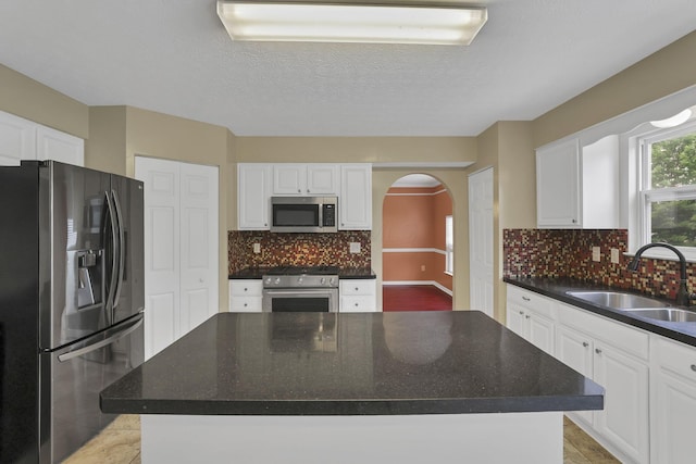 3902 Rivers Run Dr, Lewis Center, OH 43035 - kitchen with appliances with stainless steel finishes, arched walkways, white cabinetry, decorative backsplash, and a textured ceiling