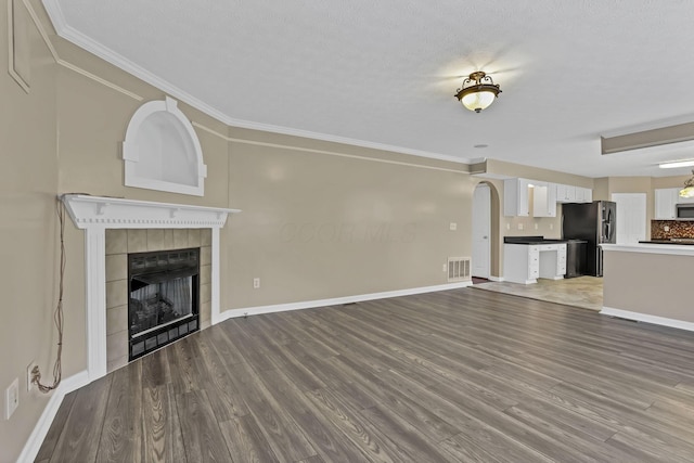3902 Rivers Run Dr, Lewis Center, OH 43035 - unfurnished living room featuring a tiled fireplace, arched walkways, ornamental molding, and wood finished floors