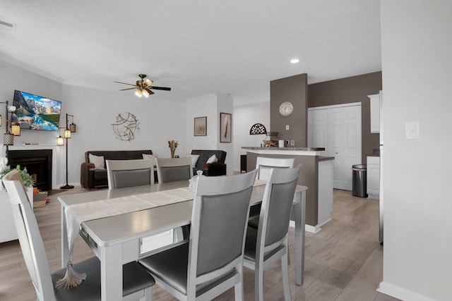 3388 Smileys Cor, Hilliard, OH 43026 - dining area with light wood-style flooring, a fireplace, a ceiling fan, and recessed lighting