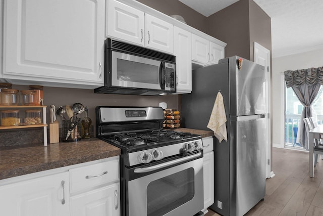 3388 Smileys Cor, Hilliard, OH 43026 - kitchen with stainless steel appliances, dark countertops, white cabinetry, light wood finished floors, and crown molding
