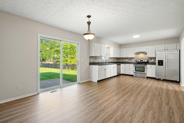 1771 Fern Trail Dr, Lancaster, OH 43130 - kitchen featuring appliances with stainless steel finishes, dark countertops, light wood-style flooring, and a textured ceiling