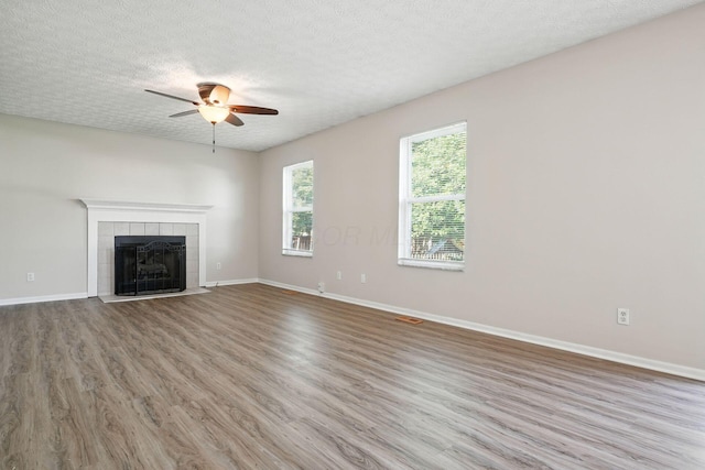 1771 Fern Trail Dr, Lancaster, OH 43130 - unfurnished living room with a tiled fireplace, a ceiling fan, wood finished floors, and a textured ceiling
