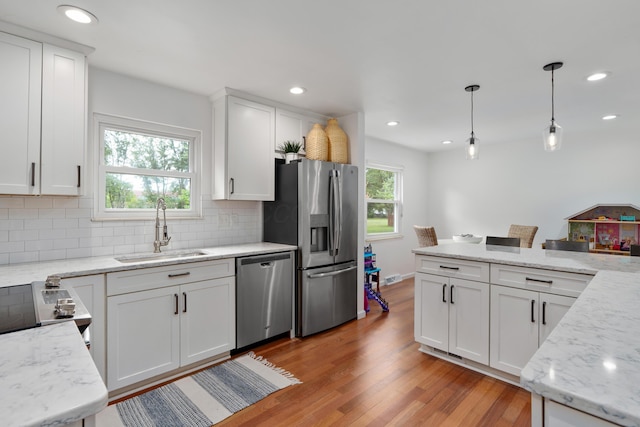 6853 Cedar Brook Pl, New Albany, OH 43054 - kitchen featuring stainless steel appliances, light wood finished floors, backsplash, white cabinetry, and decorative light fixtures