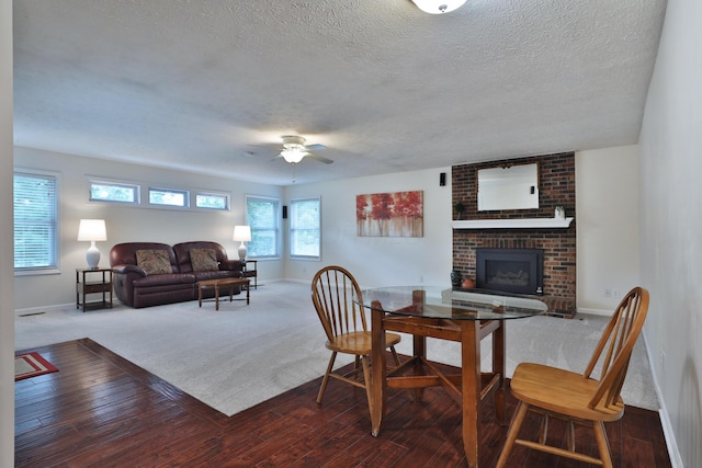2253 Otter Ln, Dublin, OH 43016 - living room with ceiling fan, a textured ceiling, a brick fireplace, dark colored carpet, and dark wood-style floors