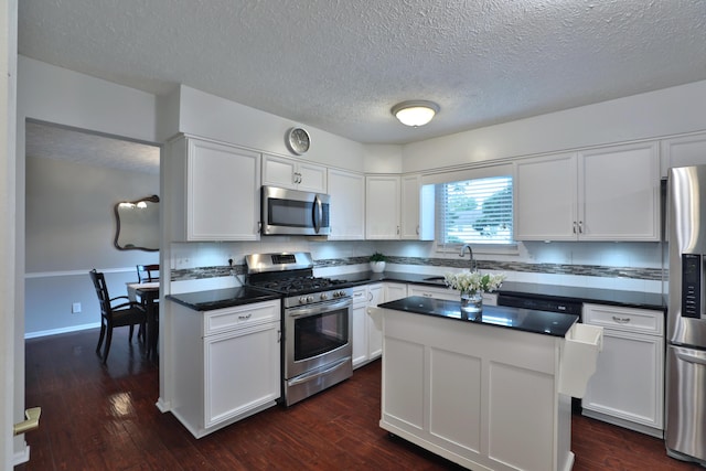 2253 Otter Ln, Dublin, OH 43016 - kitchen featuring stainless steel appliances, dark countertops, white cabinetry, a textured ceiling, and dark wood-style flooring