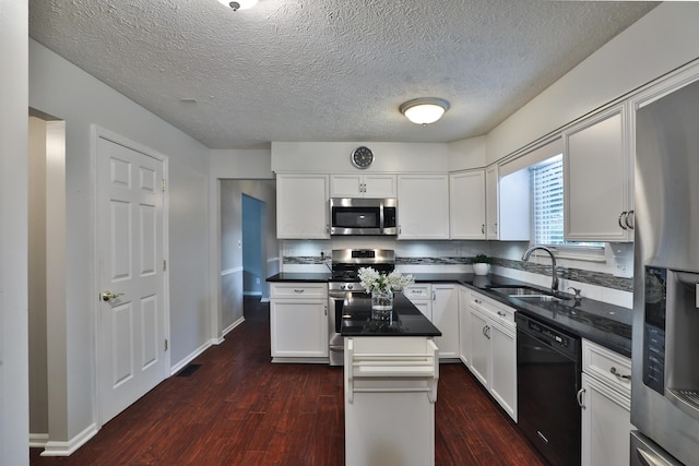 2253 Otter Ln, Dublin, OH 43016 - kitchen featuring appliances with stainless steel finishes, a center island, dark wood-type flooring, dark countertops, and white cabinets