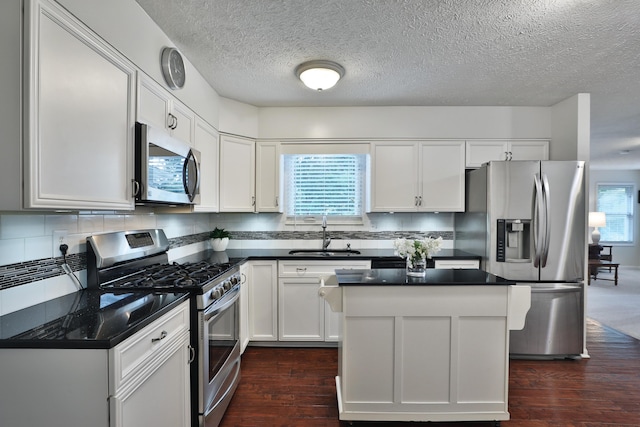 2253 Otter Ln, Dublin, OH 43016 - kitchen with appliances with stainless steel finishes, dark wood-style floors, dark countertops, tasteful backsplash, and a textured ceiling