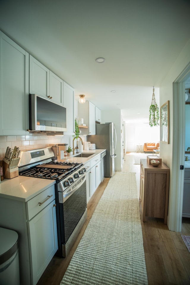 853 Thurman Ave, Columbus, OH 43206 - kitchen with appliances with stainless steel finishes, white cabinetry, wood finished floors, light countertops, and decorative backsplash