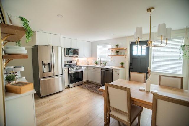 853 Thurman Ave, Columbus, OH 43206 - kitchen featuring stainless steel appliances, open shelves, a chandelier, light wood-type flooring, and white cabinetry