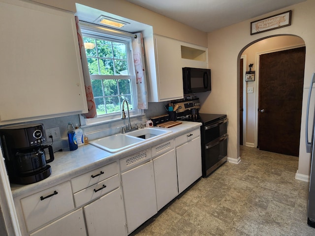 850 Grafton Rd, Newark, OH 43055 - kitchen with double oven range, black microwave, arched walkways, white cabinetry, and light countertops