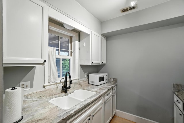 253 Kossuth St Unit H, Columbus, OH 43223 - kitchen featuring white microwave, white cabinetry, light stone counters, and light wood-style flooring