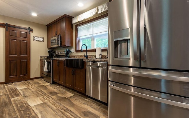 19366 Laurel Run Rd, Nelsonville, OH 45764 - kitchen featuring stainless steel appliances, a barn door, wood finished floors, dark stone countertops, and dark brown cabinetry
