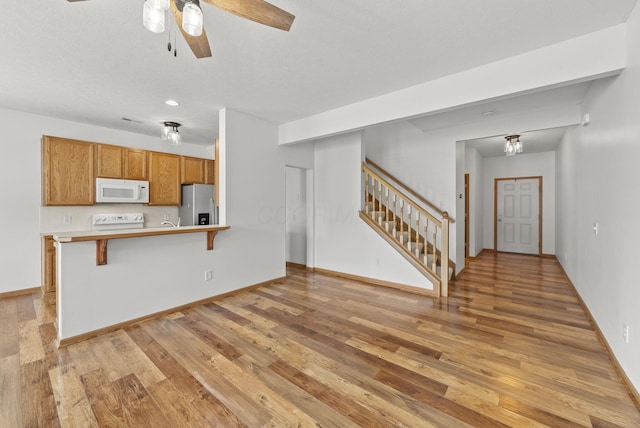 3734 Gibbstone Dr, Columbus, OH 43204 - kitchen with white microwave, stainless steel refrigerator with ice dispenser, light wood-type flooring, brown cabinets, and recessed lighting