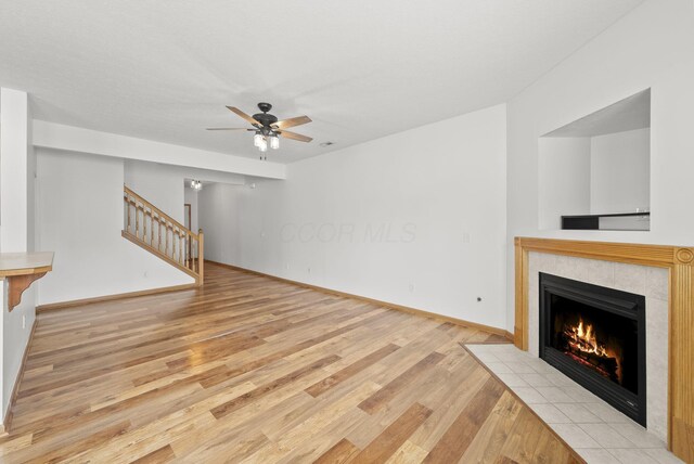 3734 Gibbstone Dr, Columbus, OH 43204 - unfurnished living room with a tiled fireplace, light wood finished floors, stairs, and a ceiling fan