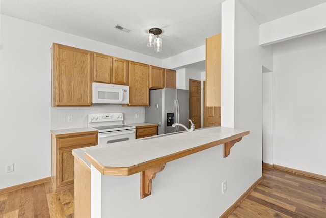 3734 Gibbstone Dr, Columbus, OH 43204 - kitchen featuring white appliances, a breakfast bar, a peninsula, light wood-style floors, and light countertops