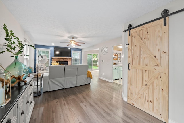 2387 Sutter Pkwy, Dublin, OH 43016 - living area featuring a barn door, ceiling fan, a textured ceiling, wood finished floors, and a warm lit fireplace
