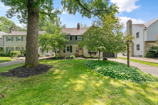 67 Aldrich Rd, Columbus, OH 43214 - colonial inspired home with concrete driveway, a garage, a front lawn, stone siding, and a chimney