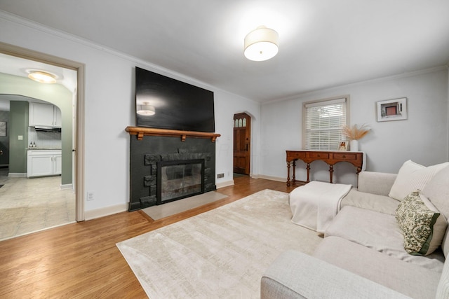 67 Aldrich Rd, Columbus, OH 43214 - living room with arched walkways, ornamental molding, a stone fireplace, and light wood-type flooring