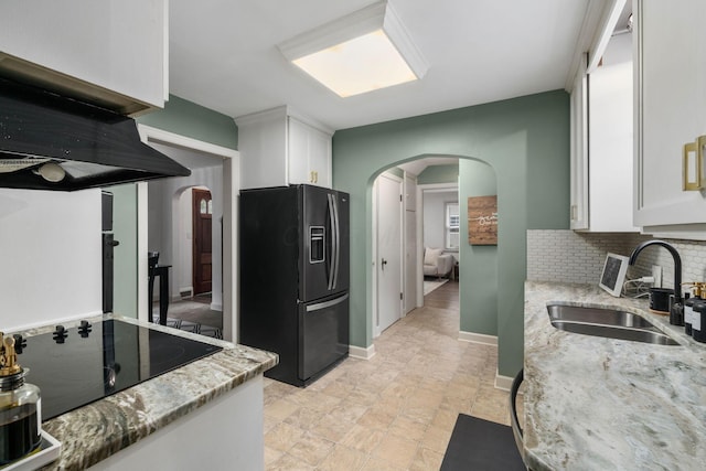 67 Aldrich Rd, Columbus, OH 43214 - kitchen featuring fridge with ice dispenser, arched walkways, white cabinetry, and light stone countertops