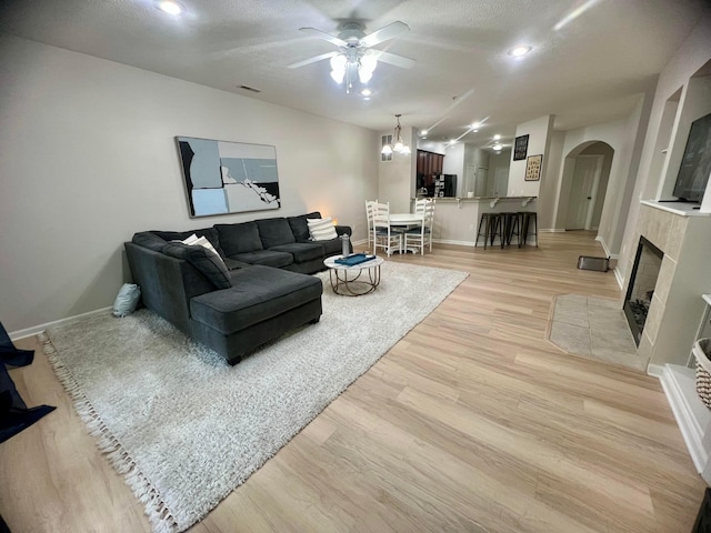 6090 Sowerby Ln, Westerville, OH 43081 - living area with arched walkways, ceiling fan, light wood finished floors, a tile fireplace, and a textured ceiling