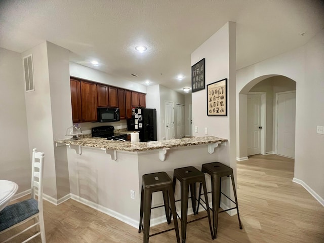 6090 Sowerby Ln, Westerville, OH 43081 - kitchen featuring black appliances, light stone countertops, arched walkways, a peninsula, and recessed lighting