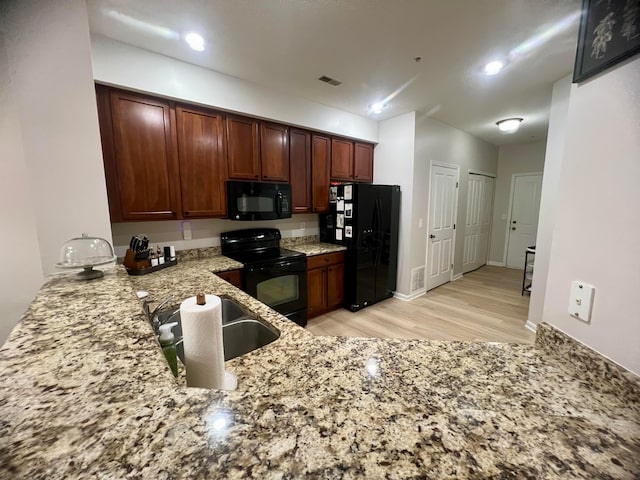 6090 Sowerby Ln, Westerville, OH 43081 - kitchen featuring black appliances, light stone counters, light wood-style flooring, and a peninsula
