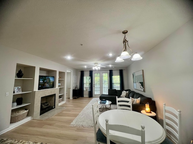 6090 Sowerby Ln, Westerville, OH 43081 - living room with light wood-type flooring, ceiling fan, built in features, a textured ceiling, and a tile fireplace