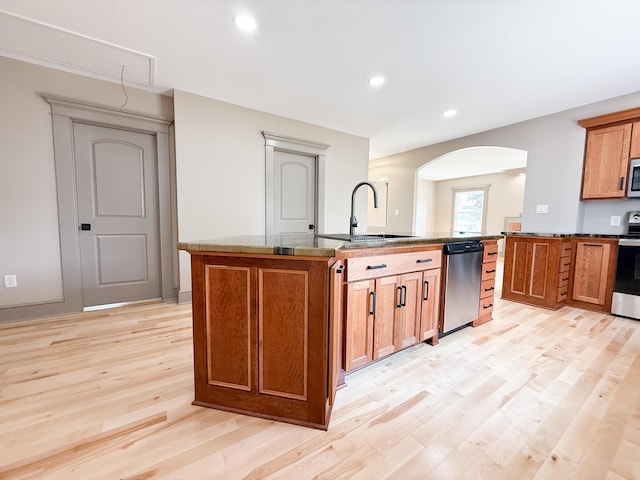 69 N Cherry St, Mount Gilead, OH 43338 - kitchen featuring stainless steel appliances, light wood-style floors, brown cabinets, arched walkways, and a center island with sink