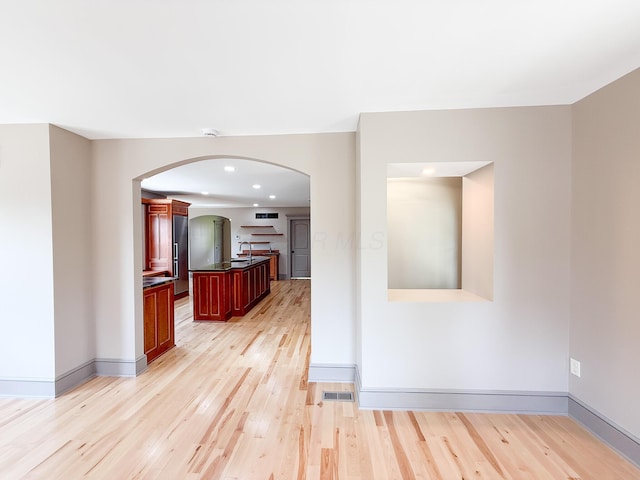 69 N Cherry St, Mount Gilead, OH 43338 - kitchen with arched walkways, dark brown cabinets, light wood-style flooring, freestanding refrigerator, and dark countertops