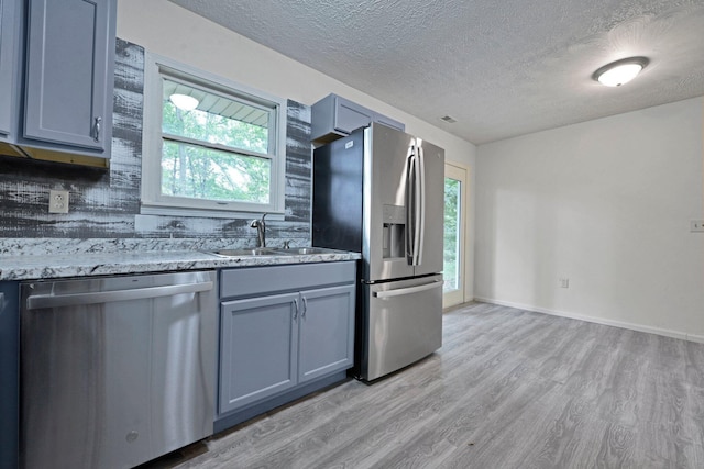 1142 Rozelle Creek Rd, Chillicothe, OH 45601 - kitchen featuring stainless steel appliances, light wood-type flooring, a textured ceiling, healthy amount of natural light, and light stone countertops