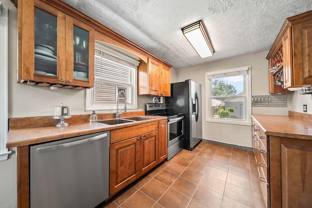 1467 Melrose Ave, Columbus, OH 43224 - kitchen featuring appliances with stainless steel finishes, brown cabinets, glass insert cabinets, and a textured ceiling