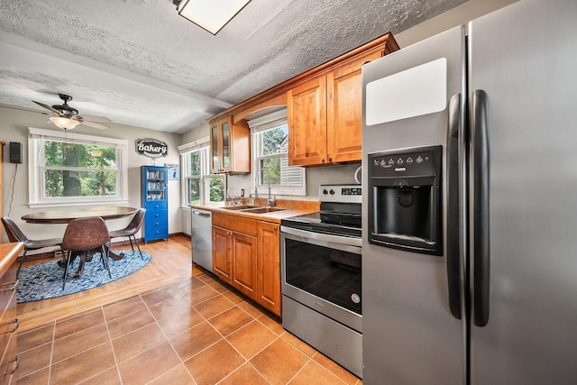 1467 Melrose Ave, Columbus, OH 43224 - kitchen featuring appliances with stainless steel finishes, brown cabinetry, healthy amount of natural light, and a textured ceiling