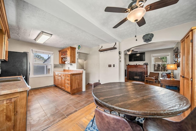 1467 Melrose Ave, Columbus, OH 43224 - dining area with ceiling fan, a fireplace, a textured ceiling, and arched walkways