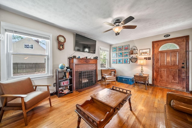 1467 Melrose Ave, Columbus, OH 43224 - living area with a fireplace, plenty of natural light, light wood-style flooring, a ceiling fan, and a textured ceiling