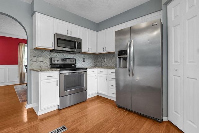 5683 Levi Kramer Blvd, Canal Winchester, OH 43110 - kitchen featuring appliances with stainless steel finishes, a textured ceiling, light stone counters, light wood finished floors, and white cabinetry