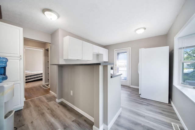 2272 Eden Ave, Columbus, OH 43224 - kitchen with freestanding refrigerator, white cabinets, healthy amount of natural light, and light wood finished floors