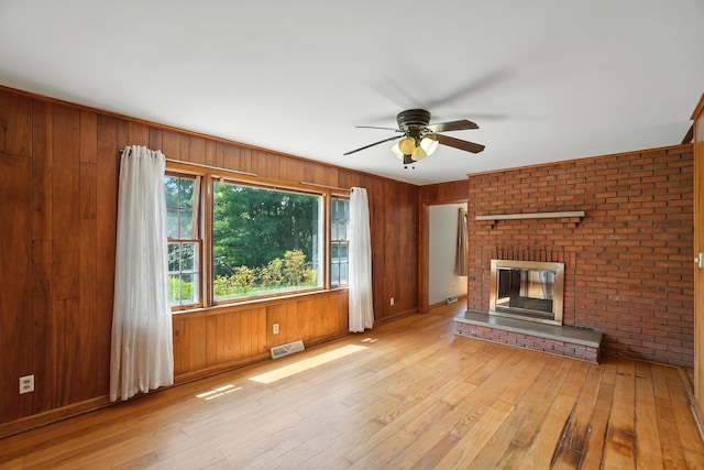 899 Meadowview Dr, Columbus, OH 43224 - unfurnished living room featuring light wood-type flooring, ceiling fan, a fireplace, and wooden walls