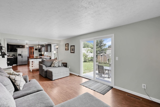 664 Dukewell Pl, Galloway, OH 43119 - living area featuring dark wood finished floors, a textured ceiling, and a chandelier
