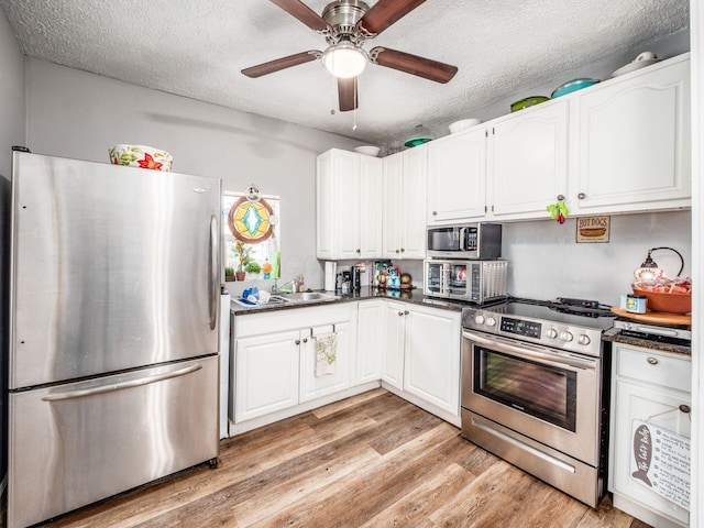 2640-2642 W Broad St, Columbus, OH 43204 - kitchen featuring stainless steel appliances, dark countertops, white cabinetry, light wood-style flooring, and a textured ceiling