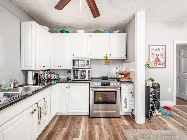 2640-2642 W Broad St, Columbus, OH 43204 - kitchen featuring stainless steel appliances, dark countertops, white cabinets, light wood-style floors, and a textured ceiling