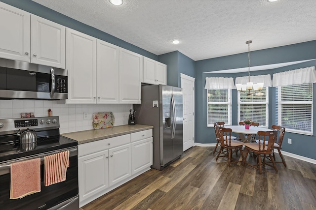 6041 Tetlin Field Dr, New Albany, OH 43054 - kitchen with appliances with stainless steel finishes, dark wood-style floors, white cabinets, a chandelier, and a textured ceiling