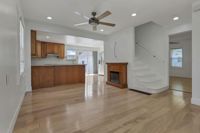 1808 Brentnell Ave, Columbus, OH 43219 - kitchen featuring brown cabinets, open floor plan, a ceiling fan, a peninsula, and light wood-type flooring