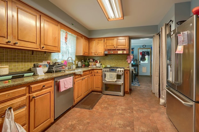 3910 Summit View Rd, Dublin, OH 43016 - kitchen featuring appliances with stainless steel finishes, under cabinet range hood, tasteful backsplash, light stone countertops, and brown cabinetry