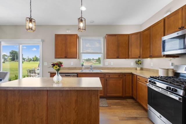 6750 Constitution Way, Powell, OH 43065 - kitchen with stainless steel appliances, light wood-style floors, decorative light fixtures, a kitchen island, and brown cabinetry