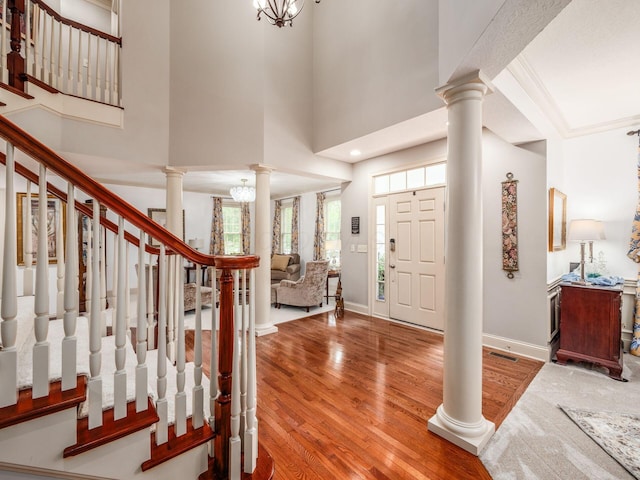 6676 Ballantrae Pl, Dublin, OH 43016 - foyer entrance featuring ornate columns, wood finished floors, a high ceiling, stairs, and a chandelier