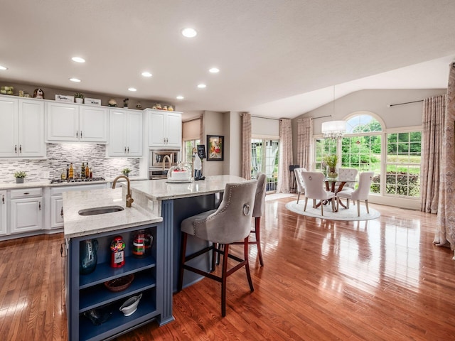 6676 Ballantrae Pl, Dublin, OH 43016 - kitchen with stainless steel appliances, white cabinetry, open shelves, lofted ceiling, and light wood finished floors