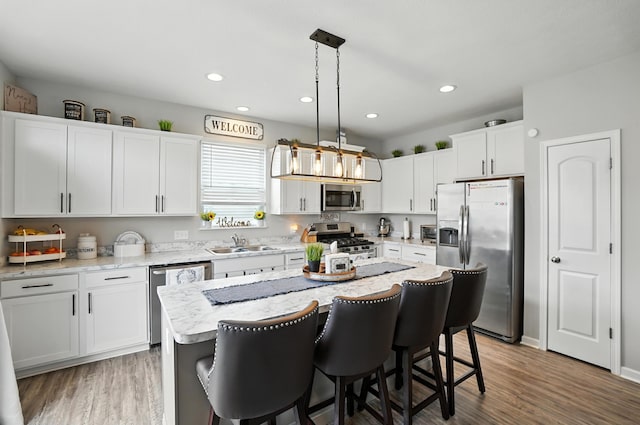 172 Rosewood Loop SE, Commercial Point, OH 43116 - kitchen with stainless steel appliances, white cabinetry, a kitchen island, a breakfast bar, and hanging light fixtures