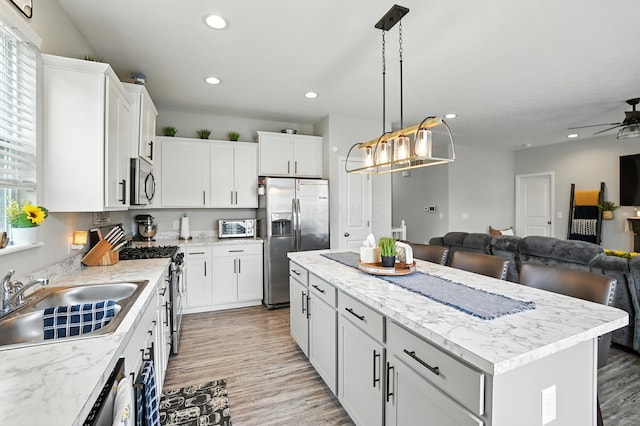 172 Rosewood Loop SE, Commercial Point, OH 43116 - kitchen with appliances with stainless steel finishes, open floor plan, light wood-type flooring, a kitchen island, and ceiling fan